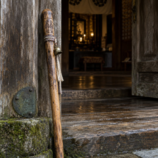 A pilgrim's cedar staff, the kongōzue, standing against a temple door at night